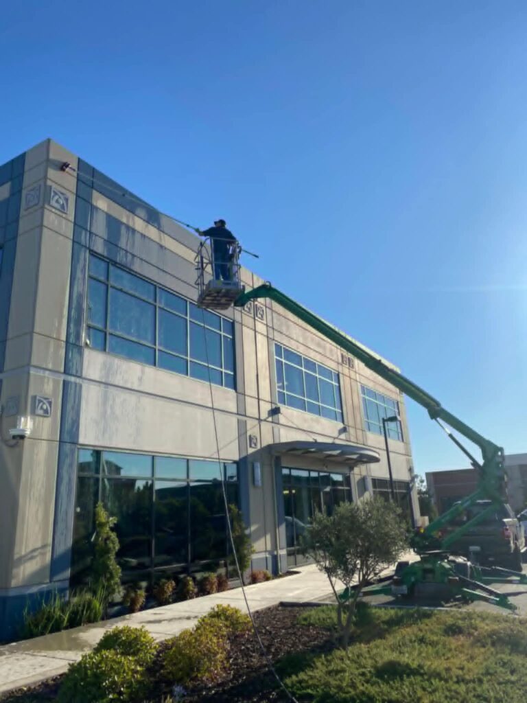 Technician soft washing a commercial building exterior in Lakewood, CO